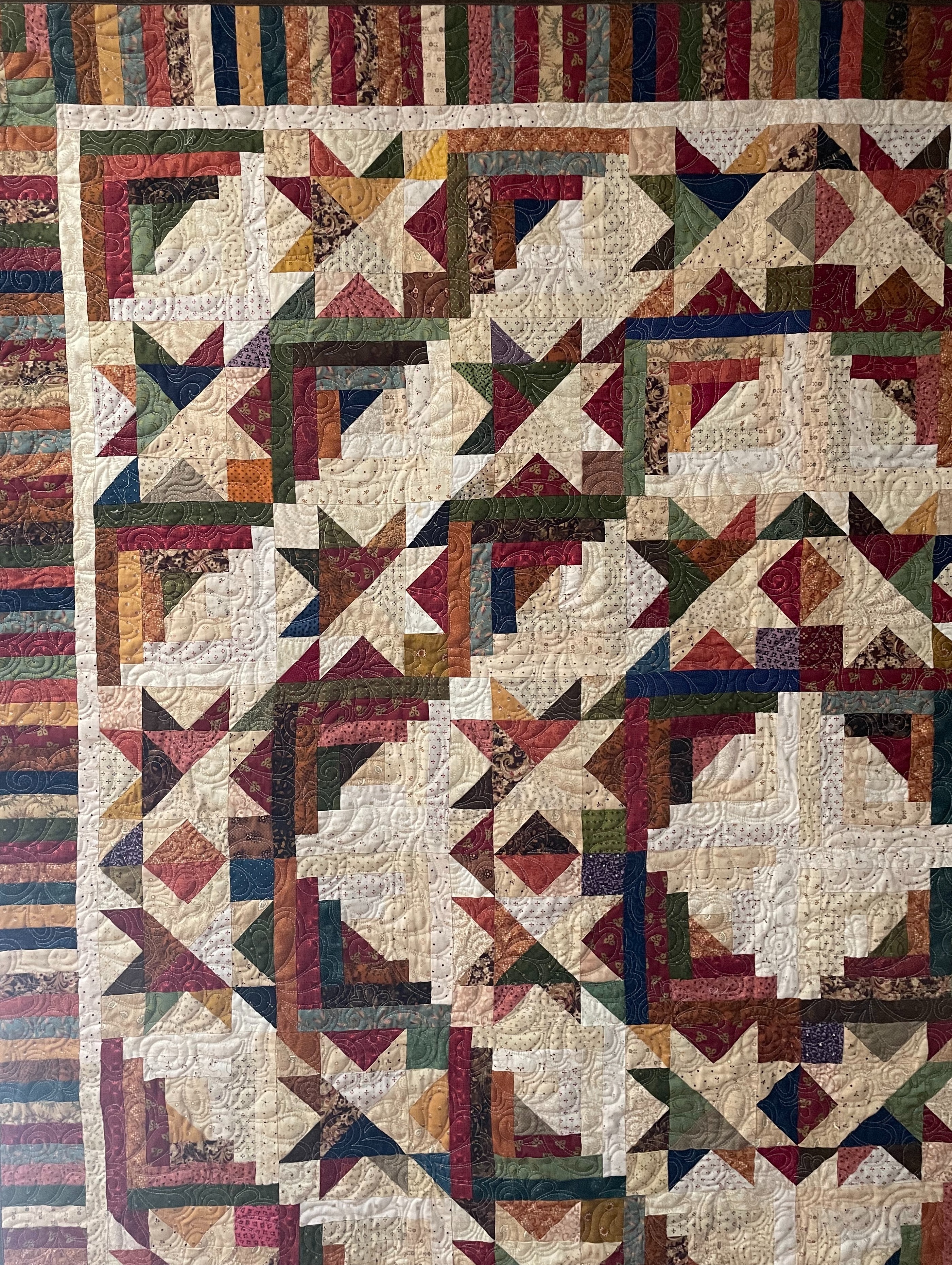 A handmade quilt draped over a chair nn a sun-filled New England porch